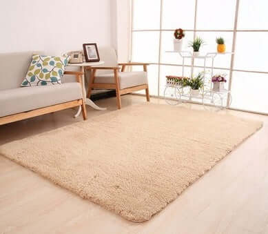 Solid beige living room rug on light wood floor, enhancing a cozy and stylish European-American decor.