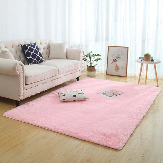 Silky fluffy pink carpet rug in a cozy living room with a sofa and decorative pillow.