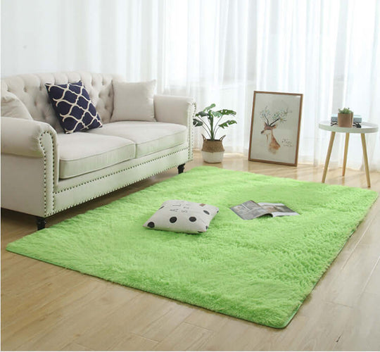 Silky fluffy green carpet rug in a living room with a couch, decorative pillows, and a coffee table.