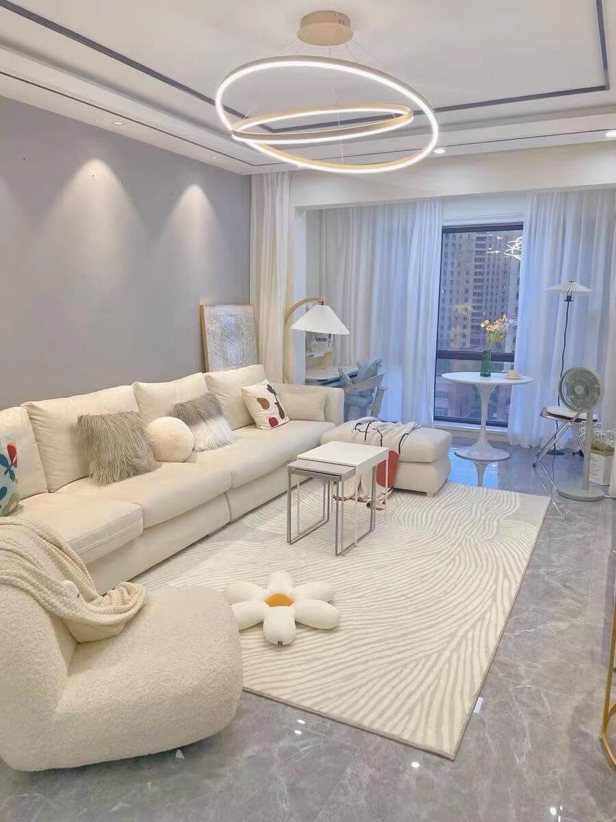 Modern living room with a stylish sofa, round light fixture, and elegant decor featuring a cozy rug.