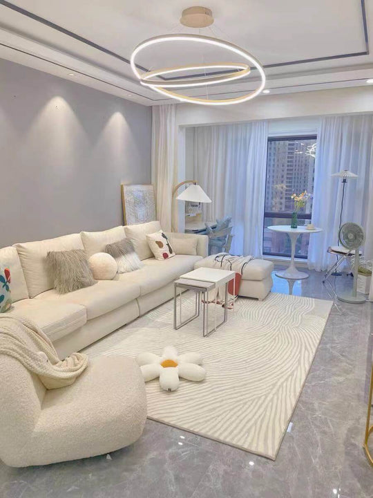 Modern living room with a stylish sofa, round light fixture, and elegant decor featuring a cozy rug.