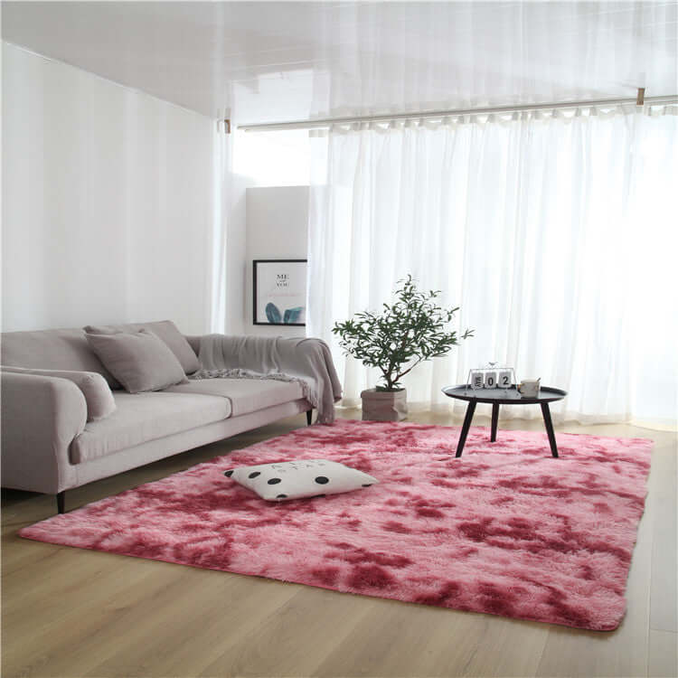 Cozy pink area rug on wooden floor in a bright living room with a gray sofa and indoor plant.